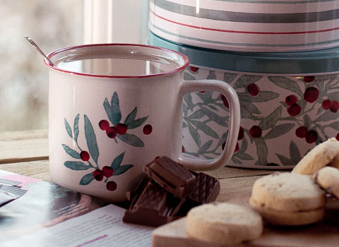 Leaf and berry design tin mug with biscuit tin behind and shortbread in front